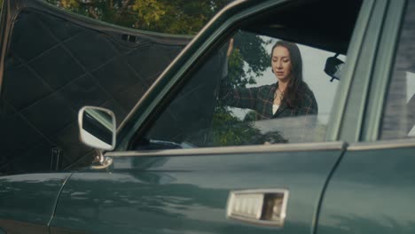 woman checking a broken-down vintage car