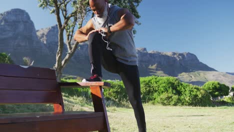 hombre afroamericano de edad avanzada haciendo ejercicios de estiramiento escuchando música