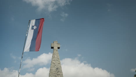 Slovenian-flag-and-stone-cross-on-the-peak-of-moutain-Donačka-gora