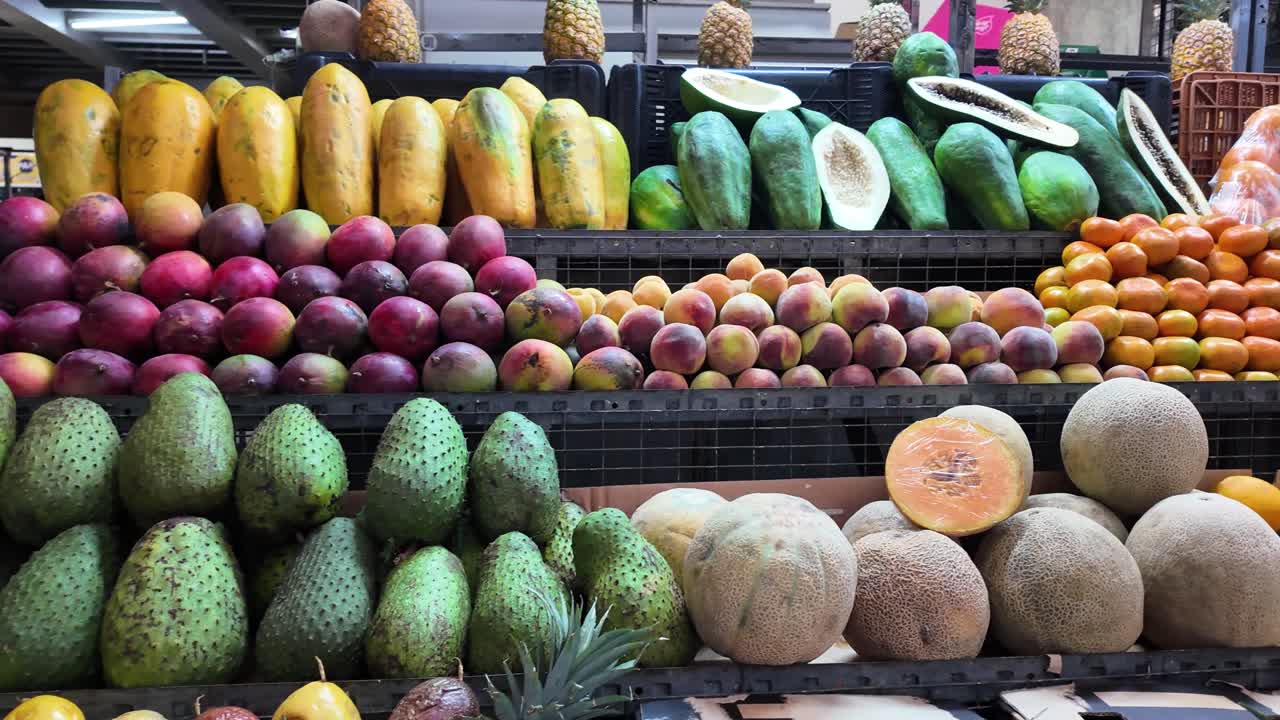 Panoramica a destra su un colorato assortimento di corossole, mango, papaie, ananas, mandarini e agrumi freschi in un mercato tradizionale