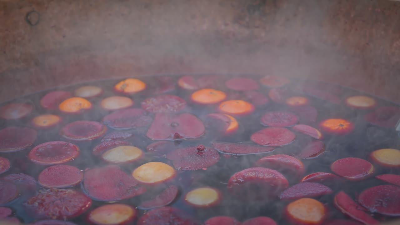 Steaming cauldron of Aromatic spiced alcoholic mulled fruity wine CLOSE-UP