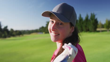 Portrait-of-female-golf-player-smiling-with-gold-club-on-her-back-on-golf-course