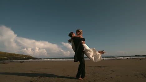 happy groom spinning his bride on the beach