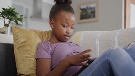 happy african american girl using smartphone on couch in slow motion