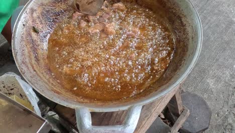 close-up of stirring a rich brown sauce in a wok with a metal spatula.