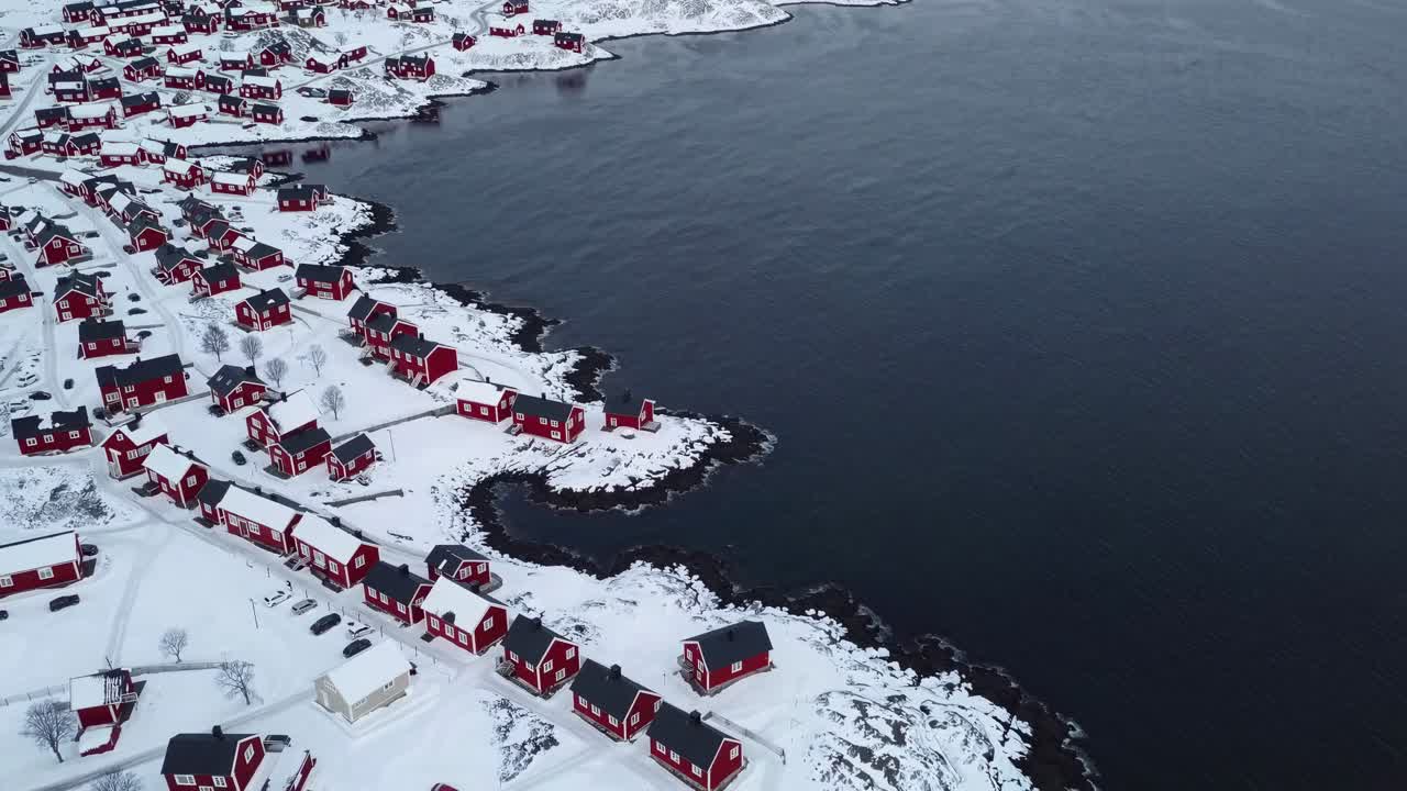 Røde hytter i et snødekt kystlandskap