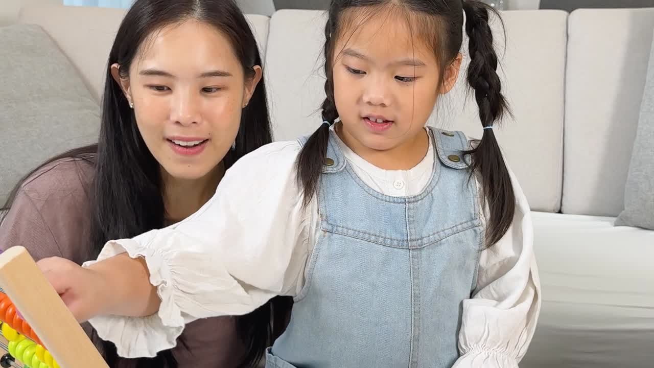 어린 소녀와 엄마가 나무 주판을 사용하여 교육적인 놀이에 참여하고 있습니다.