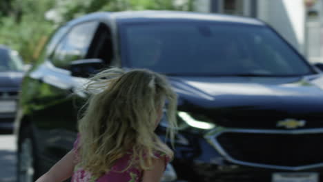 una joven saludando al coche antes de cruzar la calle.