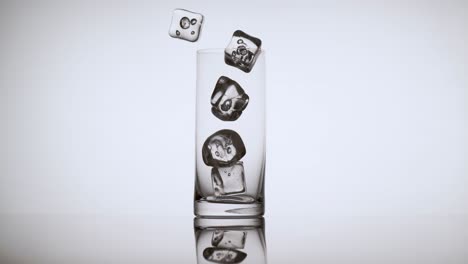 varios cubitos de hielo cayendo en un vaso vacío