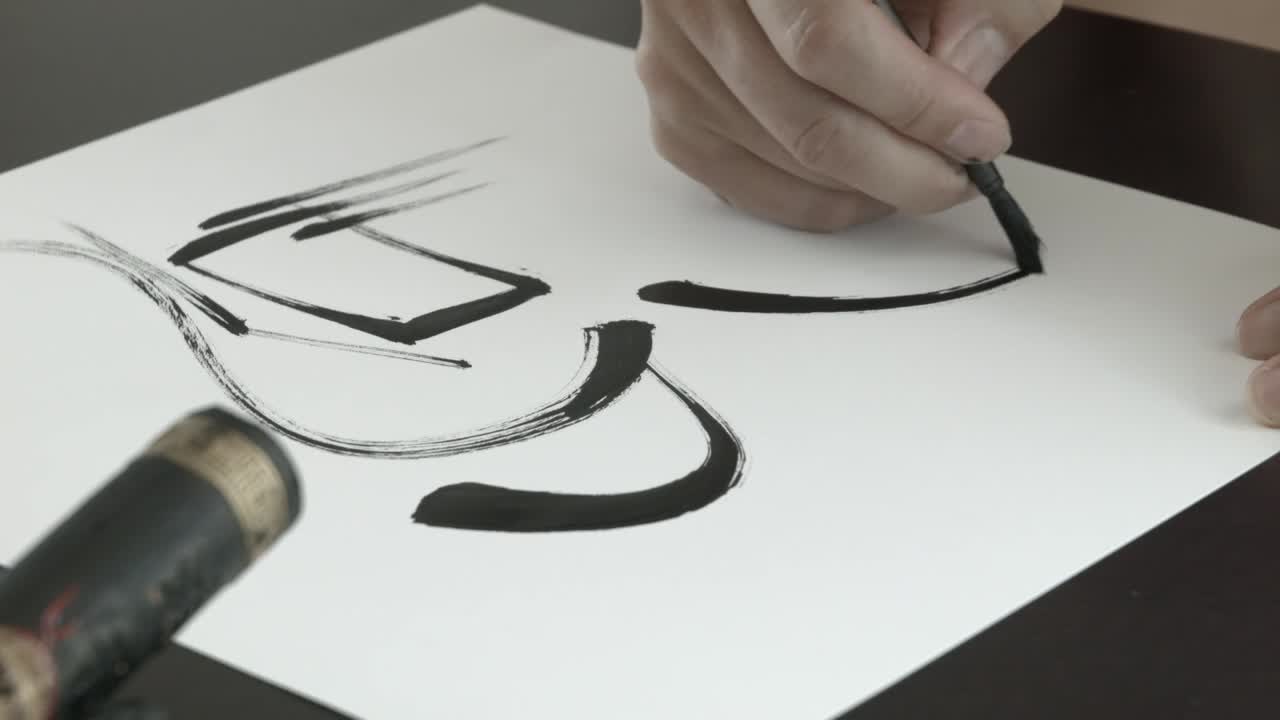 CU shot of hand drawing calligraphy strokes on white paper.