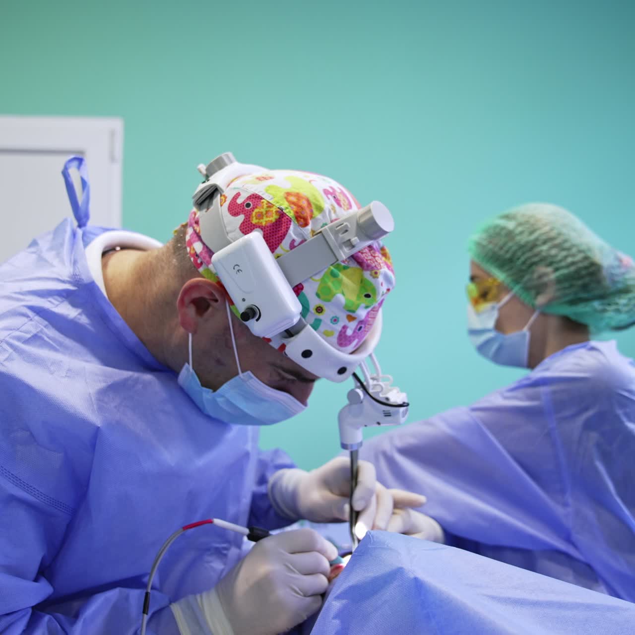 Médico de mediana edad con frontal cambiando instrumentos durante la cirugía. Una médica ayudante pasa un dispositivo con herramientas a un cirujano. Operación estética de párpados