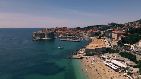 avión no tripulado volando sobre la playa de banje y las aguas azules de aqua hacia la histórica ciudad amurallada de dubrovnik, croacia
