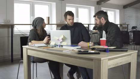 equipo de jóvenes profesionales teniendo una reunión en una oficina creativa. discusión de negocios. tazas de café y computadora portátil en la mesa. filmado en 4k