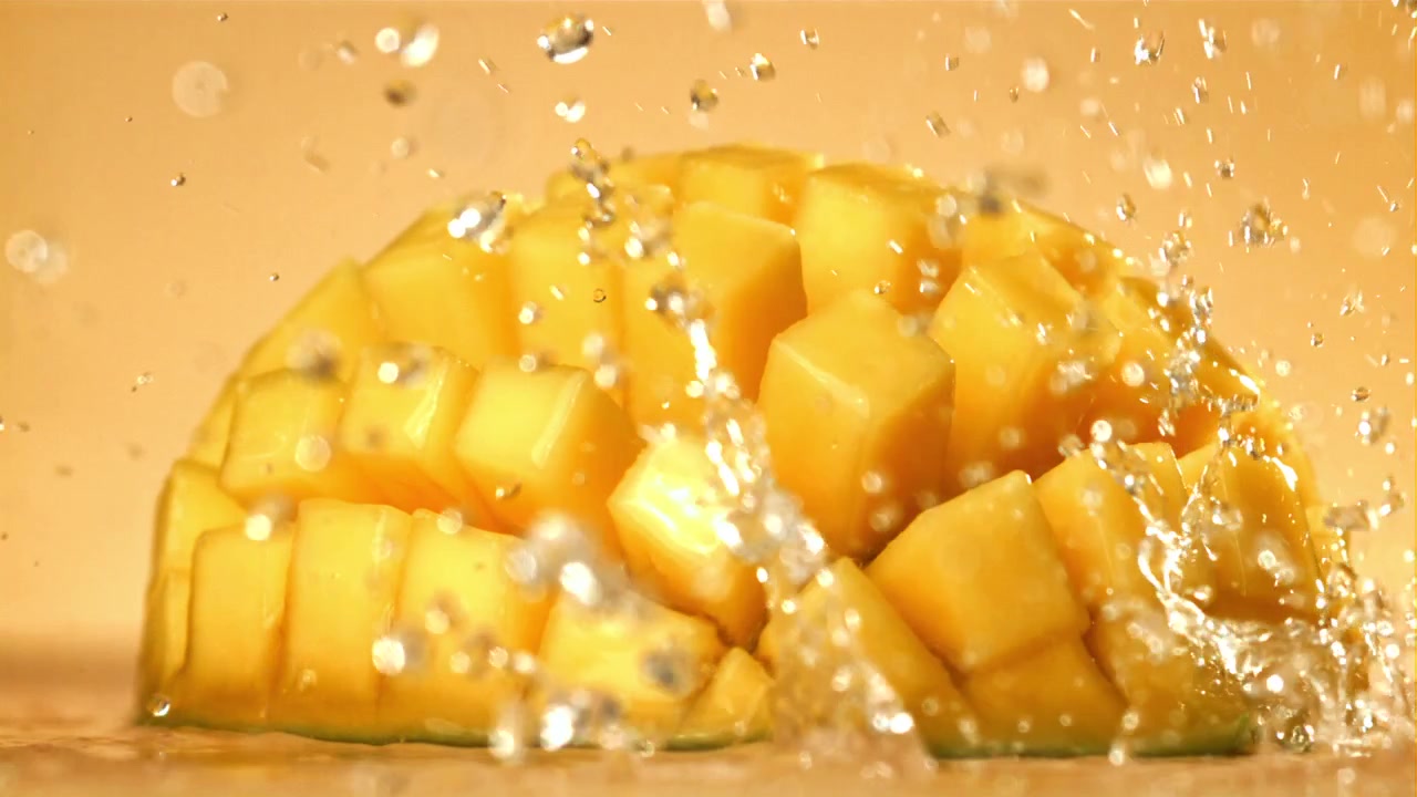 Goccioline d'acqua rinfrescanti che schizzano su cubetti di mango giallo