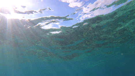 sunbeams are penetrating the surface of the caribbean sea in cozumel, mexico, creating beautiful underwater scene with light rays and cloudy sky above