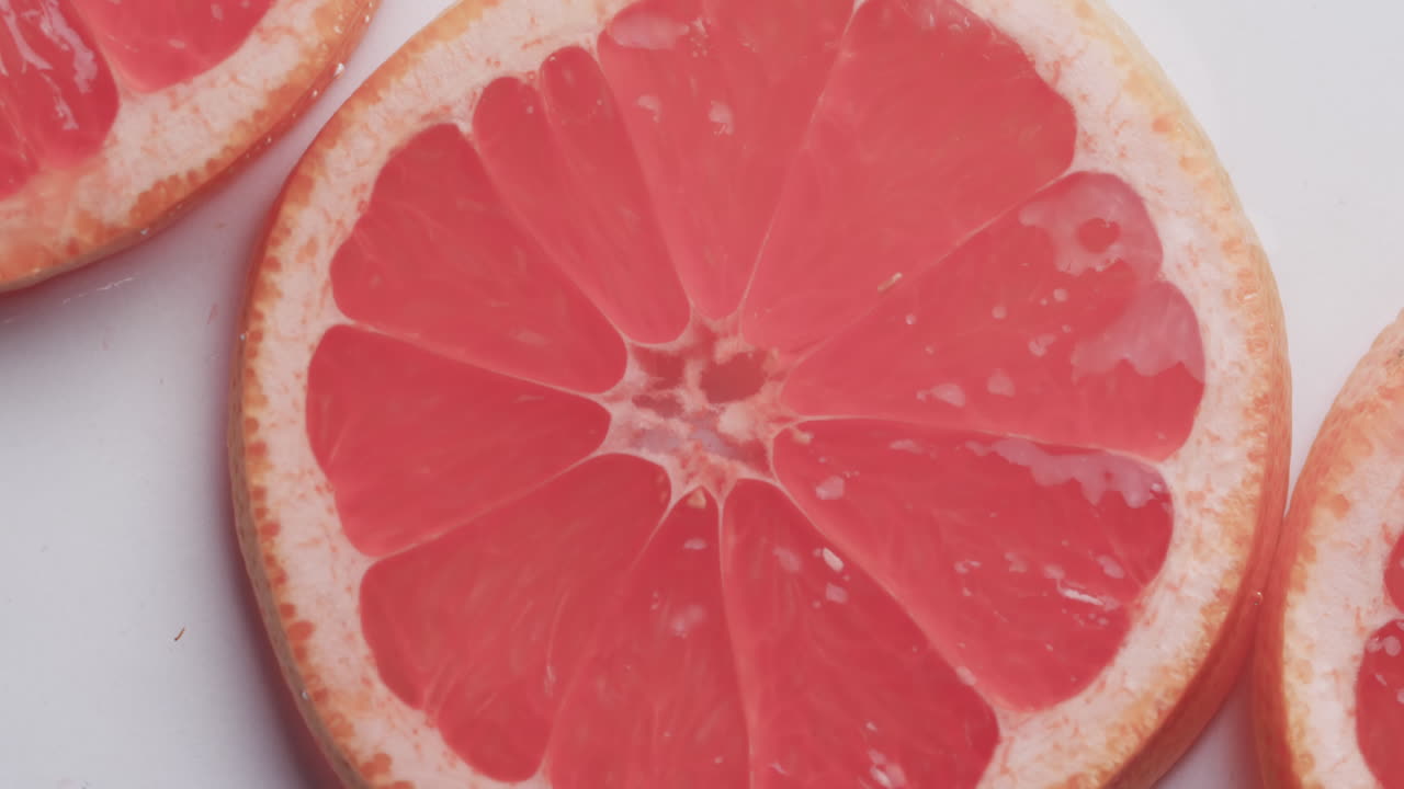 video de gotas de agua cayendo en rodajas de pomelo rojo con espacio de copia en fondo blanco