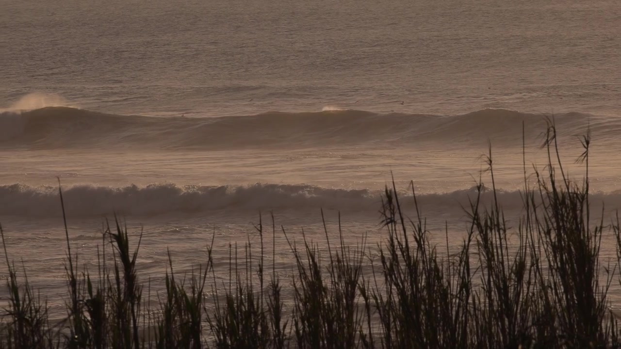 Ocean waves in slow motion at sunset panning.