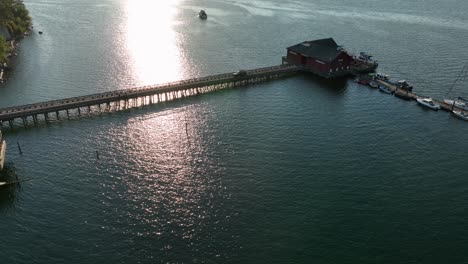 orbiting drone shot of the coupeville public dock with a truck slowly driving away after delivering goods to the restaurant