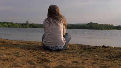 Solitary-woman-relaxing-by-lakeside-enjoying-the-view-wide-shot