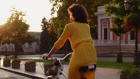 Rückansicht-Einer-Schönen-Frau,-Die-Im-Morgengrauen-Mit-Einem-Korb-Und-Blumen-Auf-Einem-Citibike-Durch-Die-Innenstadt-Fährt-Und-Ihre-Zeit-Genießt