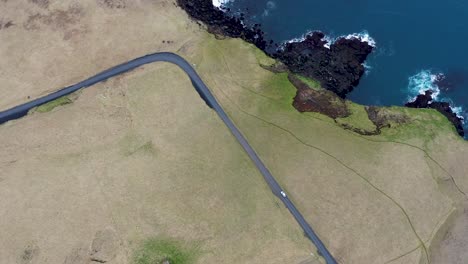 aerial shot overhead a car driving along the coast of vestmannaeyjar