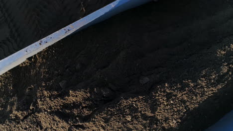 pile of dark soil in a blue metal container