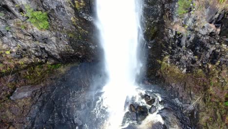Aerial-view-above-rocky,-scenic-splashing-waterfall-wilderness-aerial-pull-back-to-elevated-view