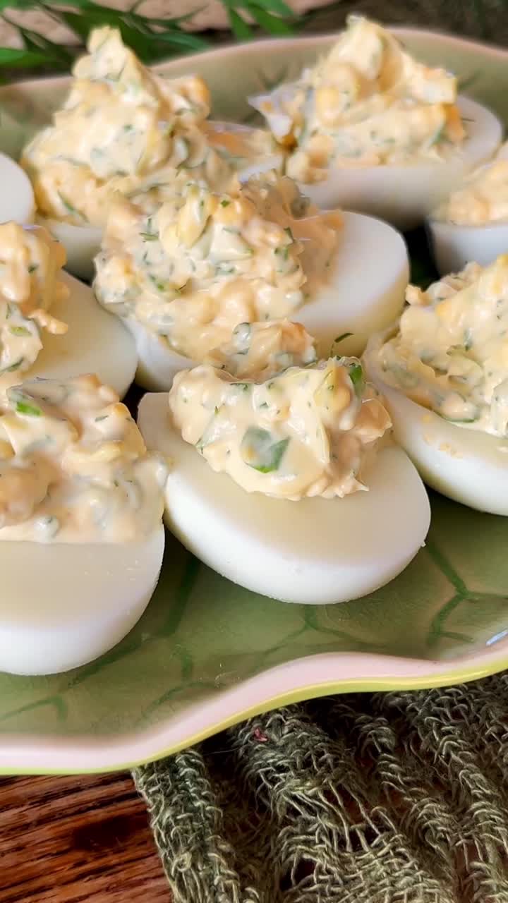 Vertical close-up of homemade deviled eggs with chunky creamy herb filling on a patterned plate, highlighting classic appetizer texture and fresh party food presentation