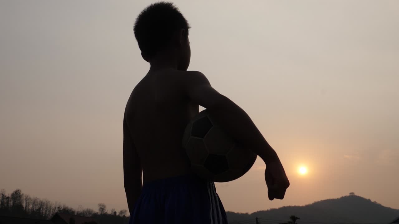 Boy with soccer ball at sunset