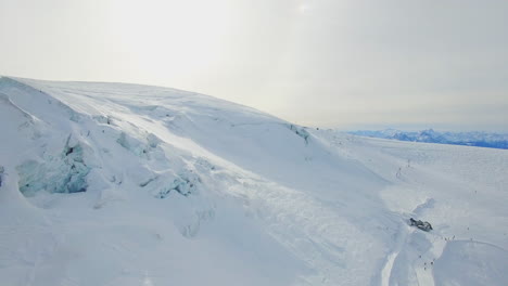 pristine snow-capped landscapes in switzerland, where the drone captures the pure beauty of the white expanse, creating a winter wonderland spectacle with some skiers in the far distance