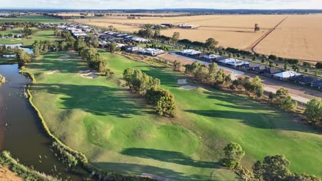 über-Wasserhindernissen-Und-Fairways-Des-Golfplatzes-Mit-Neuen-Häusern-Und-Ackerland-Dahinter