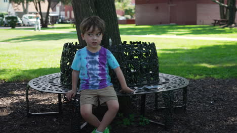 lonely kid sitting alone in a tree park bench
