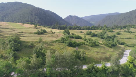 aerial: flying over arable land in a mountainous area, mountains can be seen in the background