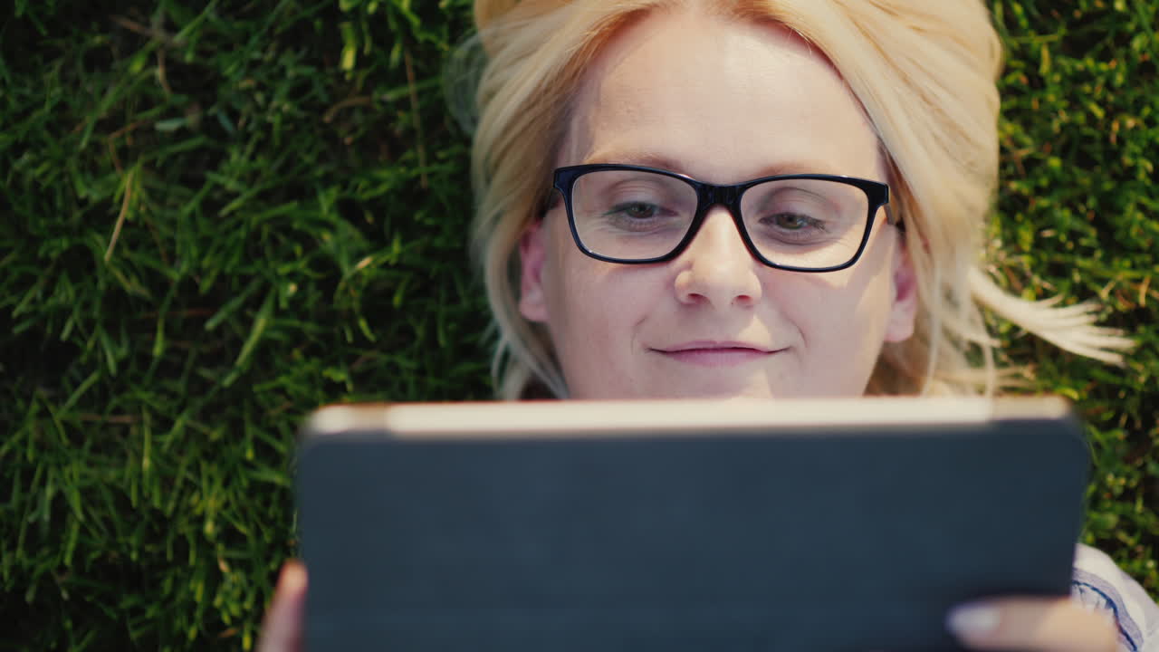 A Woman Is Using A Tablet Lying On The Lawn View From Above 4k Video
