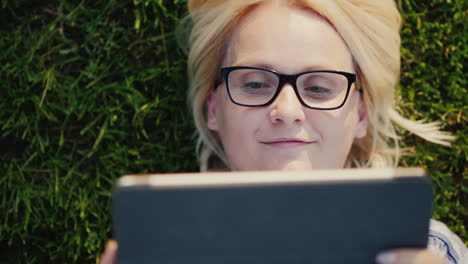una mujer está usando una tableta tirada en la vista del césped desde arriba de un video de 4k