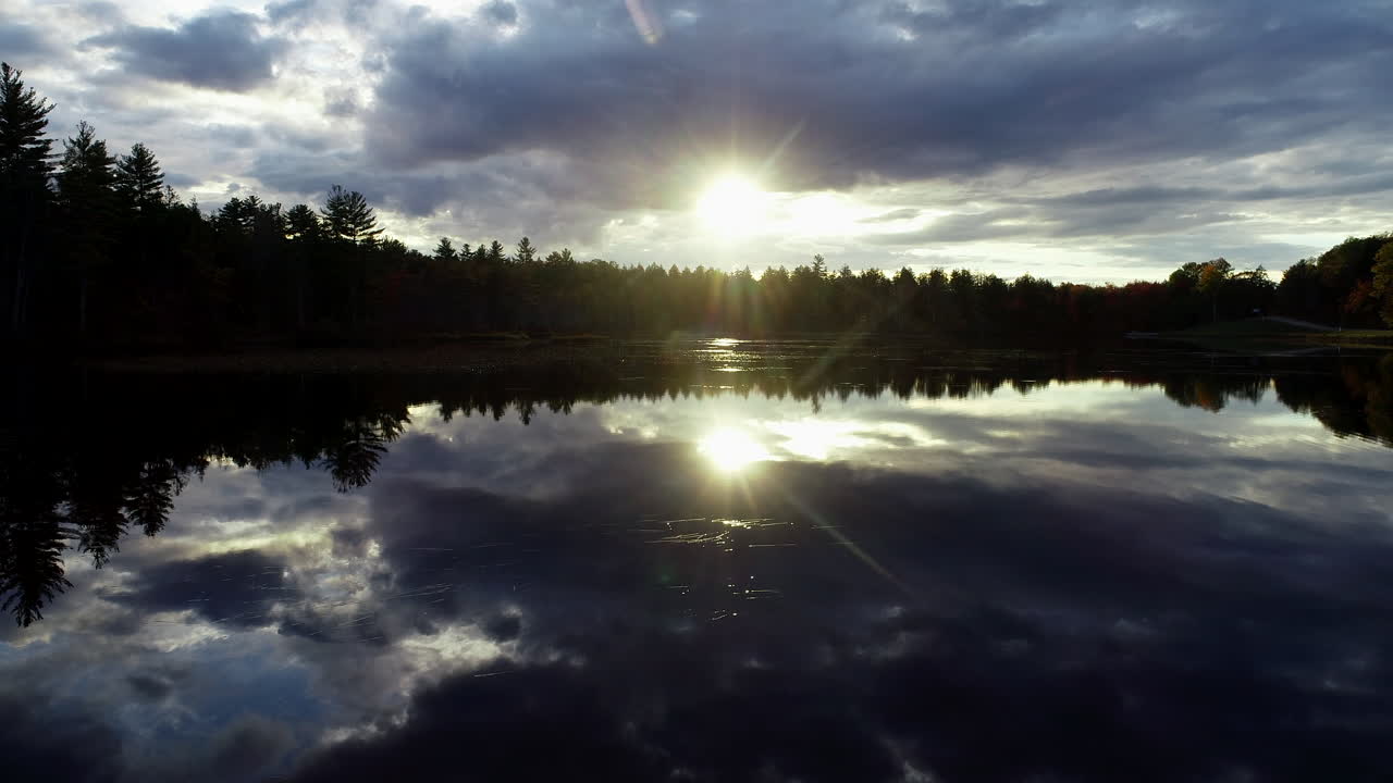 Slow moving drone shot of a sunset over a calm mirror reflective lake