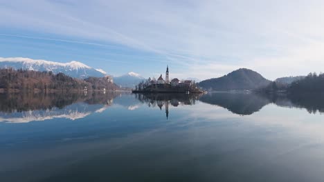 static shot of calm bled lake with mountains at background