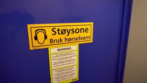 sign warning about noise zone on door to ships engine room - norwegian language on sign