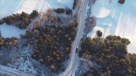 Top-Down-Shot-Of-Trucks-Driving-On-A-Snow-Covered-Rural-Road