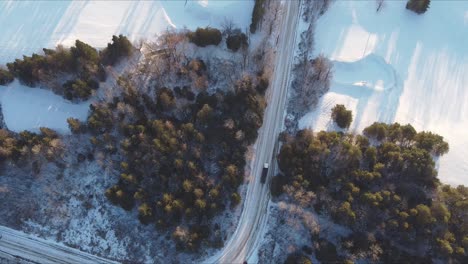 toma de arriba hacia abajo de los camiones que circulan por una carretera rural cubierta de nieve