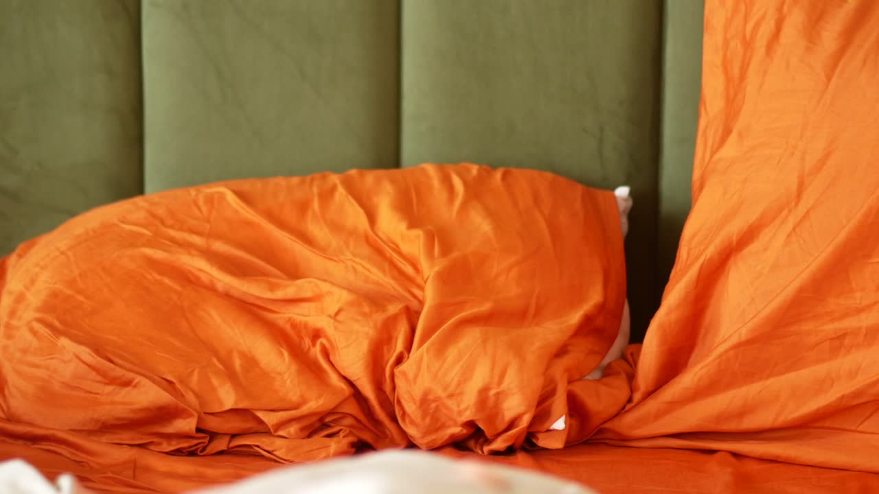 cama naranja con sábanas desordenadas