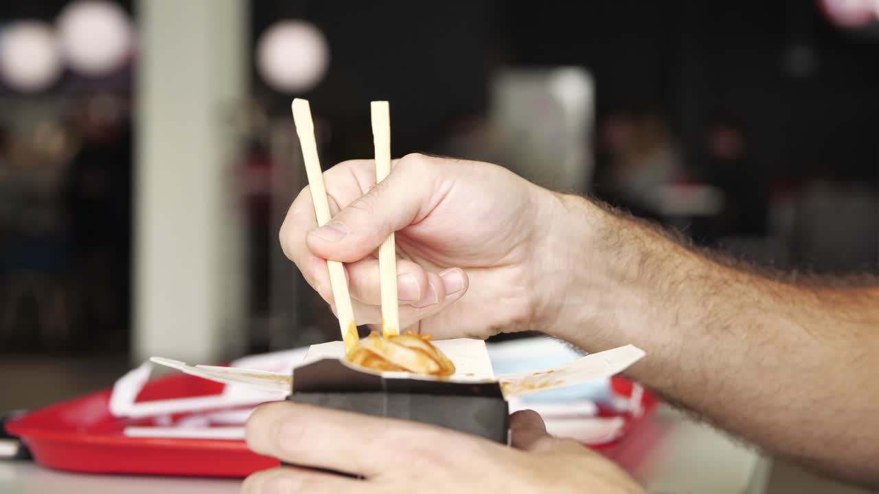 Person eating Chinese food with chopsticks