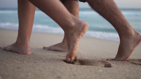 toma manual en cámara lenta de una pareja enamorada dando un paseo romántico por una playa de arena con olas tranquilas en el mar