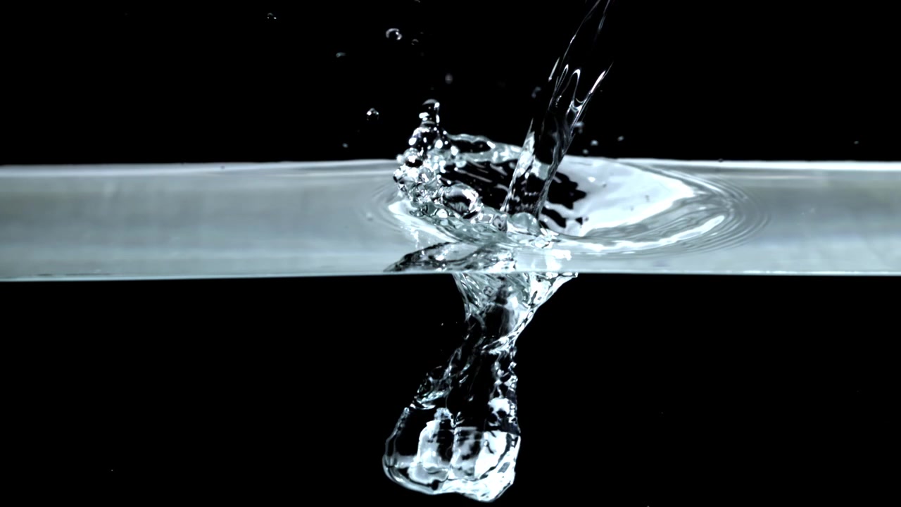 Acqua che si versa e schizza con bolle al rallentatore su sfondo nero