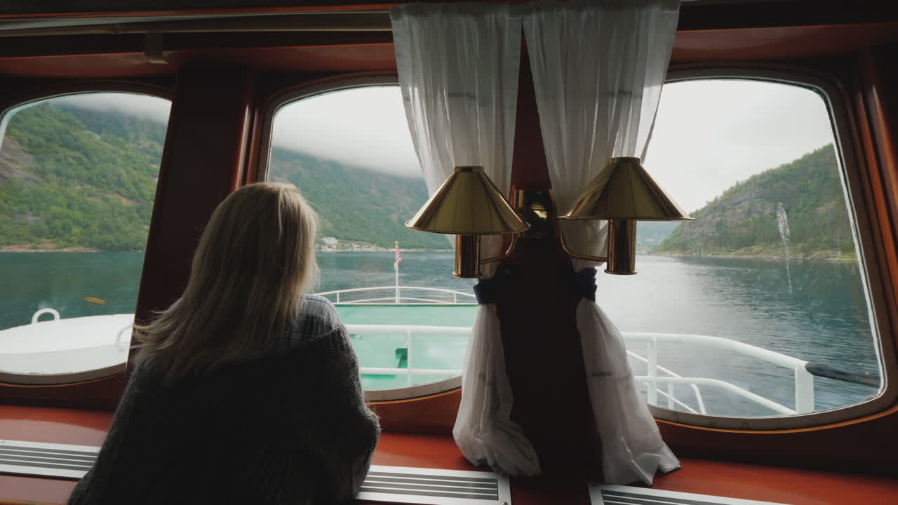 una mujer mira por el ojo de buey el hermoso paisaje de noruega flota en un barco en el noruego