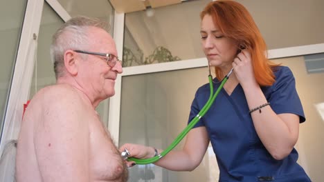 a caring female doctor examines the heart rate of a mature patient using a stethoscope during an examination in the hospital. a general practitioner uses a stethoscope while listening to an elderly man’s heartbeat