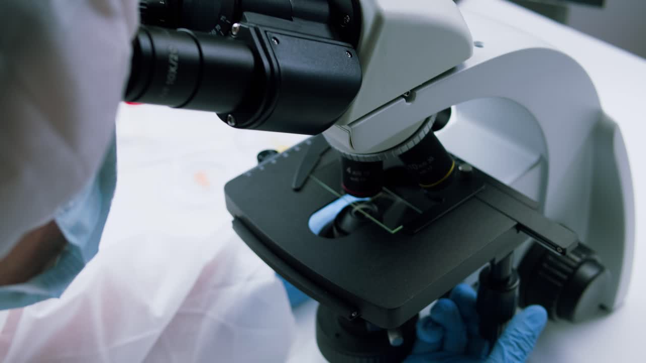 Scientist Examining Sample Through Microscope in Laboratory