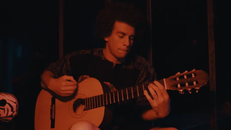 man playing acoustic guitar in the dark