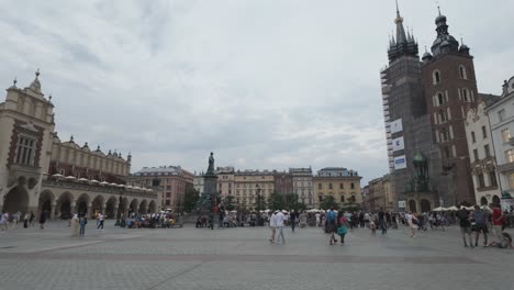 krakow's main square with crowds walking by the historic cloth hall on a cloudy day