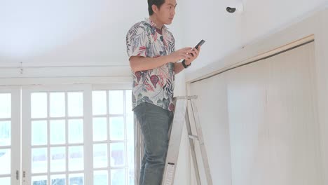 hombre asiático en una escalera usa teléfono móvil control de seguridad cámara de cctv